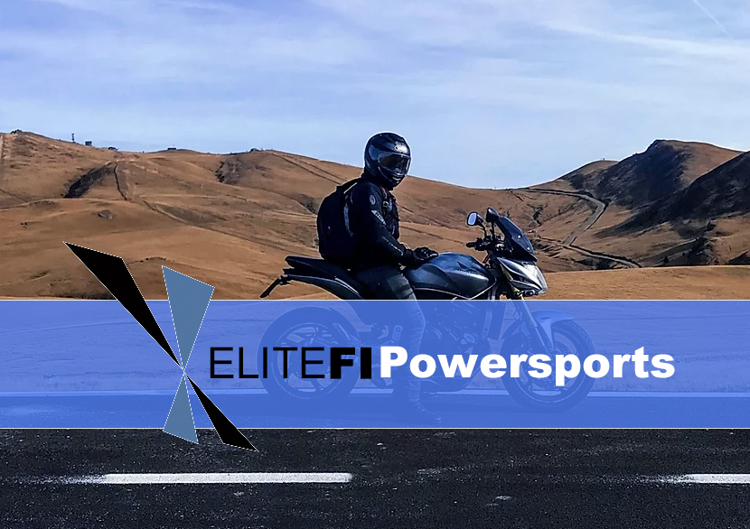 Motorcyclist in black helmet and jacket riding a motorcycle across arid desert hills under blue sky