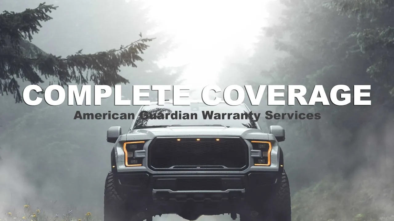 Dark pickup truck with amber headlights driving toward camera on misty forest road lined with evergreen trees.