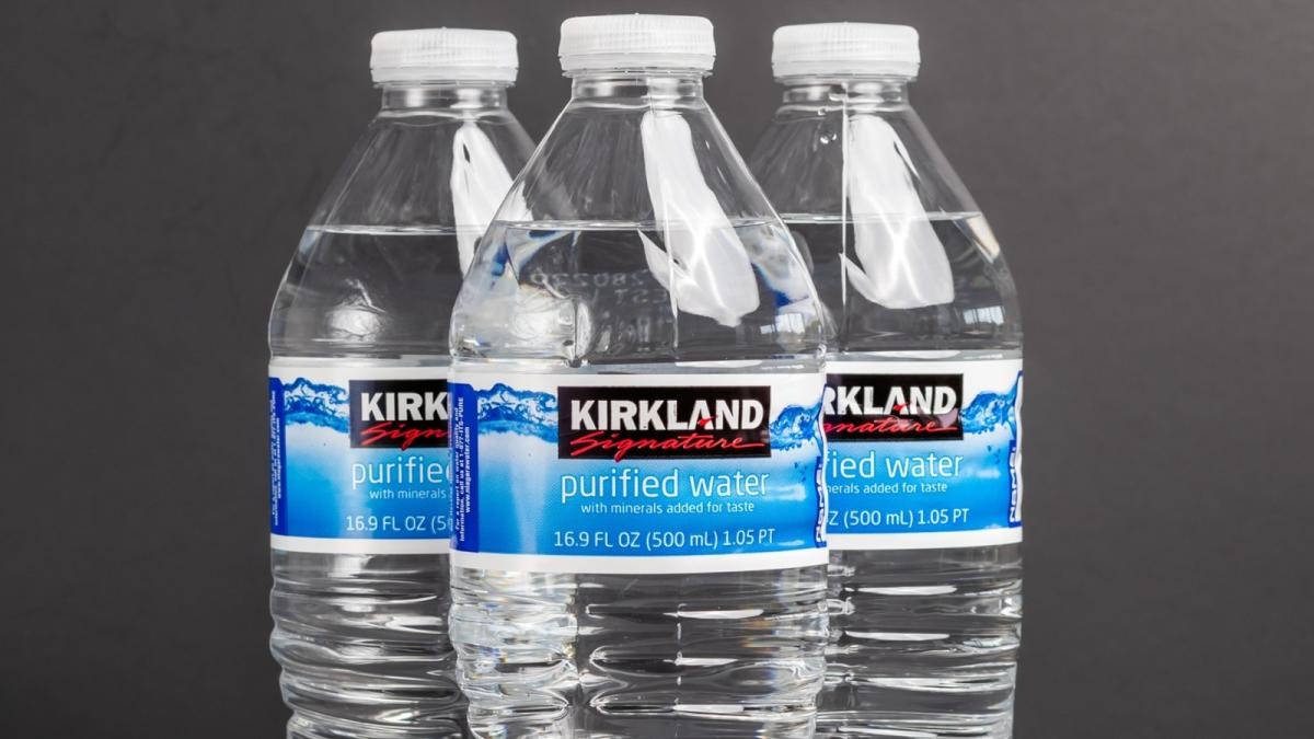 Three identical bottles of Kirkland purified water with white caps arranged in a row against a dark gray background.